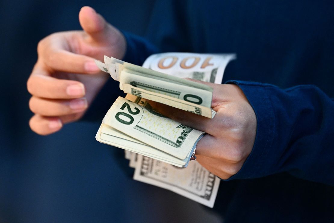 An employee counts out cash at an Apple store in Los Angeles on September 22, 2023. 