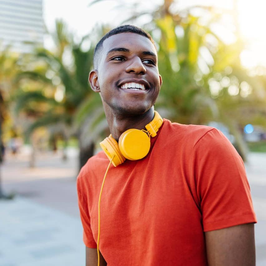 Happy man with headphones standing in the street while looking away
