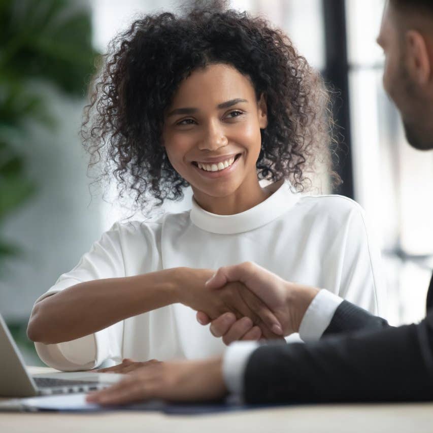 Happy loan manager shaking hands with client in modern office